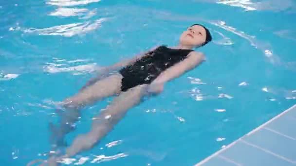 aulas de natação para crianças na piscina - bela menina de pele clara nada na água
 - Filmagem, Vídeo