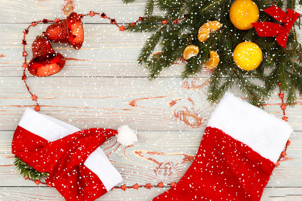 Weihnachtskomposition. Weihnachtsmuster mit Mandarinen, Tannenzweig, roter Socke als Geschenk und Glocken von oben, flacher, blauer Hintergrund, Retro-Stil, es schneit. haben Tonisierung. Kopierraum - Foto, Bild