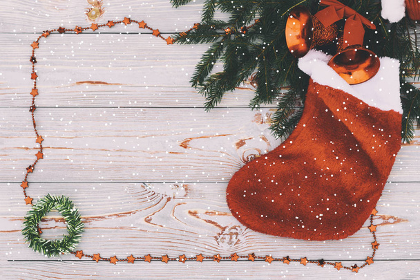 Weihnachtskomposition. Weihnachtsmuster mit Mandarinen, Tannenzweig, roter Socke als Geschenk und Glocken von oben, flacher, blauer Hintergrund, Retro-Stil, es schneit. haben Tonisierung. Kopierraum - Foto, Bild