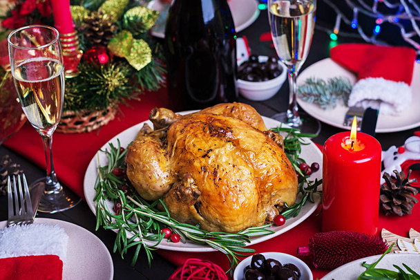 christmas table table is served with a turkey, decorated with bright tinsel and candles - Фото, изображение