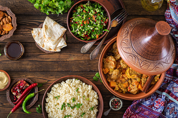 Traditional tajine dishes, couscous and fresh salad on rustic wooden table. Tagine lamb meat and pumpkin - Photo, Image