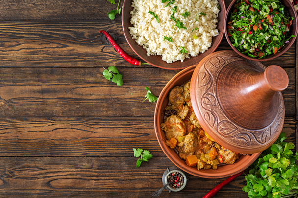 traditionelle Tajine-Gerichte, Couscous und frischer Salat auf rustikalem Holztisch. Tagine Lamm Fleisch und Kürbis - Foto, Bild