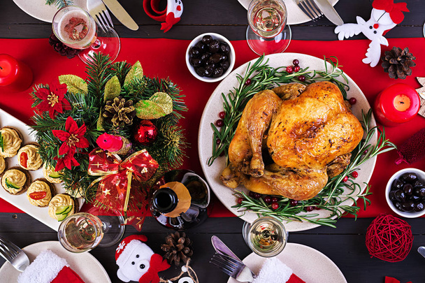 christmas table table is served with a turkey, decorated with bright tinsel and candles - Foto, Imagen