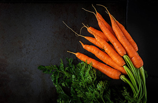 Bund frische Karotten mit grünen Blättern auf dunklem Hintergrund - Foto, Bild
