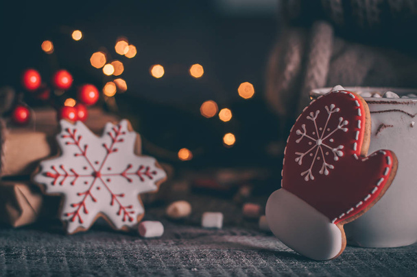 forma de biscoitos de gengibre de floco de neve e mitene e xícara de chocolate quente com marshmallow no fundo brilhante feriado
 - Foto, Imagem