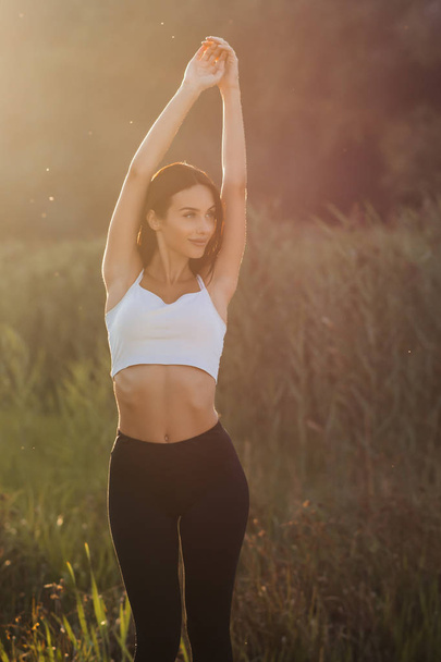 beautiful brunette doing fitness at sunrise  - Фото, изображение