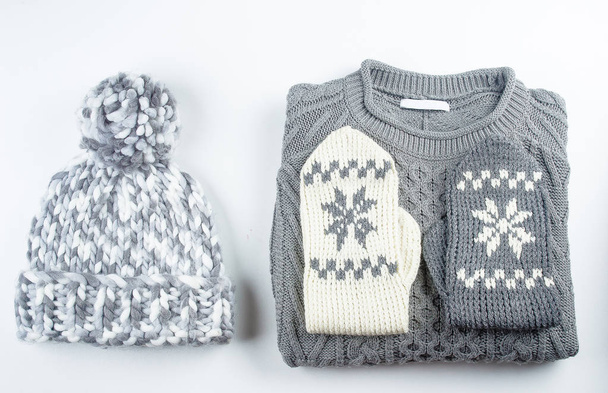 Collection of woolen knitted sweater, mittens, hat on white background table - Photo, Image