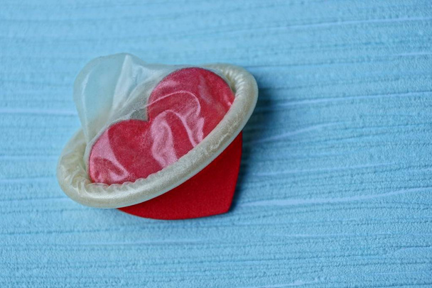 Malé červené srdce v šedém kondom na modrém pozadí - Fotografie, Obrázek