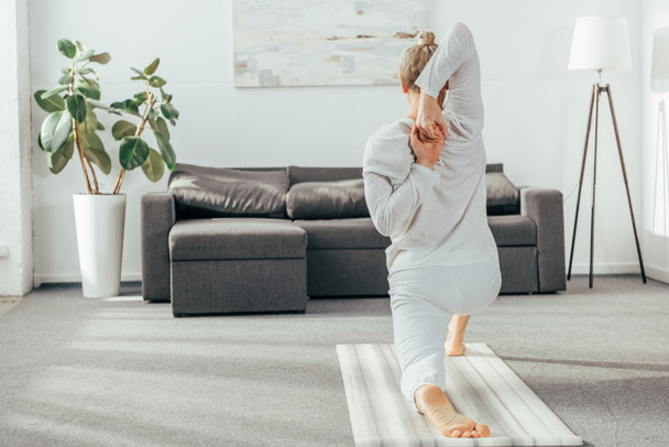 zadní pohled na člověka cvičení Crescent výpadu na koleno pose jógu doma - Fotografie, Obrázek