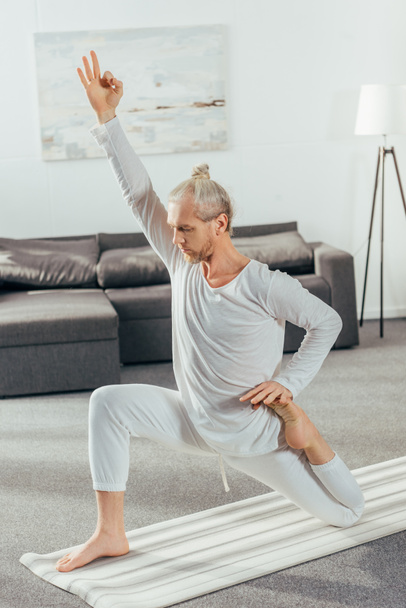 athletic flexible adult man practicing yoga on mat at home - Foto, Imagem