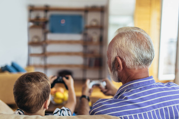Grand-père et petit-fils jouent à des jeux vidéo à la maison
. - Photo, image