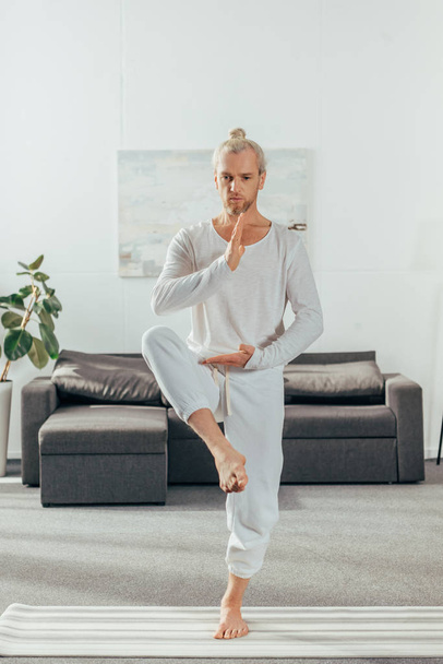sportos felnőtt ember kiegyensúlyozó jóga póz a mat otthon - Fotó, kép