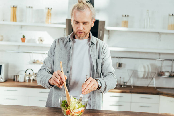 jóképű felnőtt férfi főzés otthon zöldségsaláta - Fotó, kép