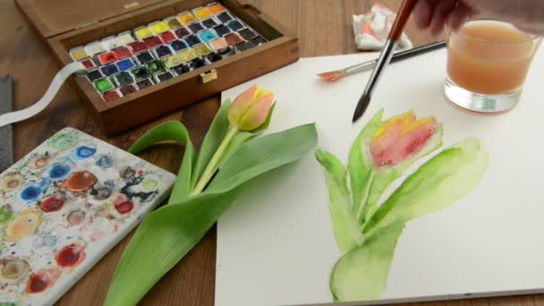 Pintura com pincel laranja tulipa bud em aquarelas e limpeza do pincel em vidro de água
. - Filmagem, Vídeo