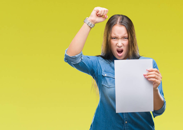 Молодая белая женщина держит чистый лист бумаги на изолированном фоне раздраженный и разочарованный кричать от гнева, сумасшедший и кричать с поднятой рукой, гнев концепции
 - Фото, изображение