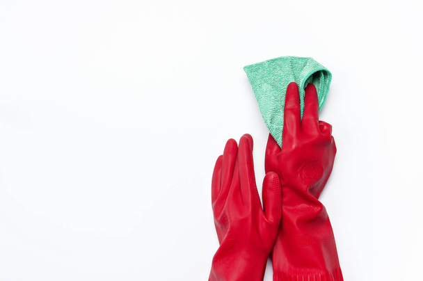 Γυναικεία χέρια σε προστατευτικά γάντια από καουτσούκ κόκκινο με ένα πανί μικροϊνών που απομονώνονται σε λευκό φόντο επίπεδης βάζει το top view αντίγραφο χώρου. Καθαρισμού έννοια, νοικοκυριό, καθαρισμού εταιρεία νοικοκυρά - Φωτογραφία, εικόνα