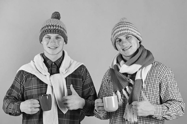 Twin brothers in warm hats and scarves hold cups - Valokuva, kuva