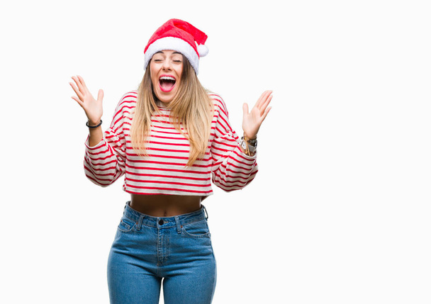 Giovane bella donna indossa cappello di Natale su sfondo isolato celebrando pazzo e pazzo per il successo con le braccia alzate e gli occhi chiusi urlando eccitato. Concetto vincitore
 - Foto, immagini