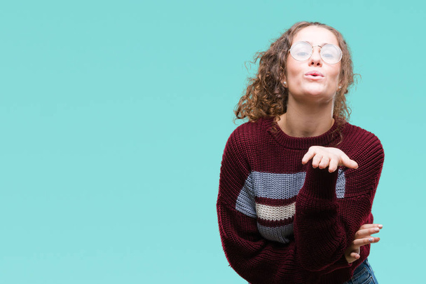 Beautiful brunette curly hair young girl wearing glasses over isolated background looking at the camera blowing a kiss with hand on air being lovely and sexy. Love expression. - Photo, Image