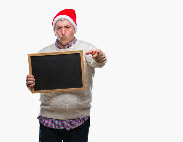 Bell'uomo anziano che indossa il cappello di Natale e tiene la lavagna su sfondo isolato puntando con il dito verso la fotocamera e verso di te, segno della mano, gesto positivo e fiducioso dal davanti
 - Foto, immagini