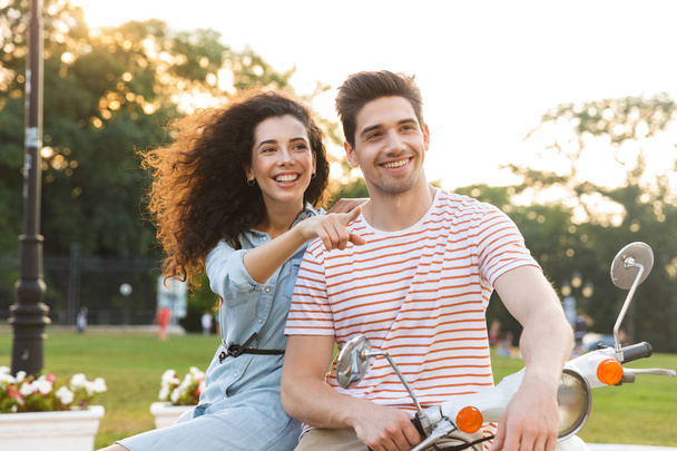 Portrait of caucasian couple man and woman sitting together on motorcycle in city park - Foto, immagini