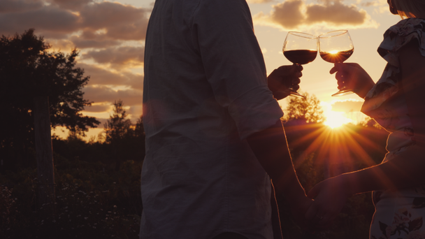 Romantische paar hand in hand clink glazen met wijn bij zonsondergang. - Video