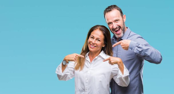 Middelbare leeftijd hispanic business paar over geïsoleerde achtergrond op zoek vertrouwen met glimlach op het gezicht, wijzen zichzelf met de vingers trots en blij. - Foto, afbeelding
