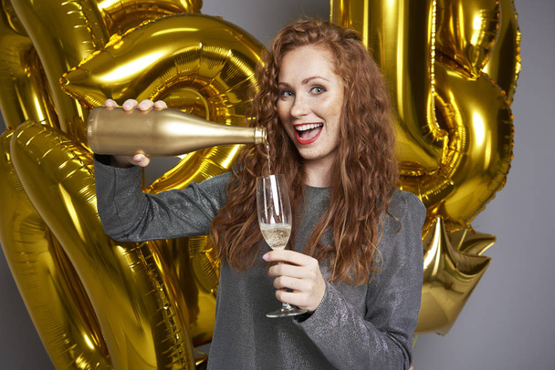 Screaming woman pouring champagne at studio shot - Photo, Image