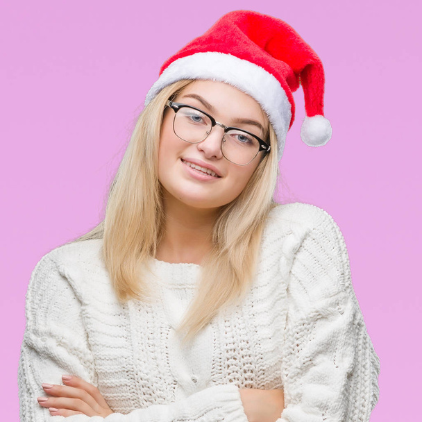 Молода біла жінка в різдвяному капелюсі над ізольованим фоном щасливе обличчя посміхається схрещеними руками, дивлячись на камеру. Позитивна особа
. - Фото, зображення