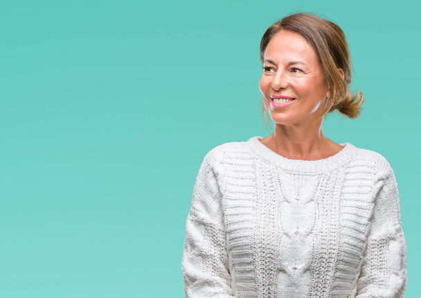 Middle age senior hispanic woman wearing winter sweater over isolated background looking away to side with smile on face, natural expression. Laughing confident. - Photo, Image