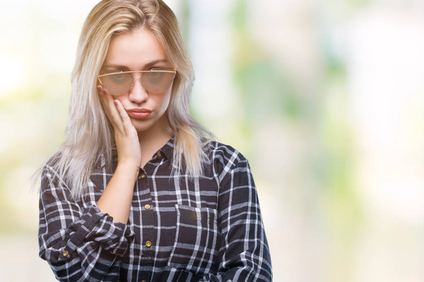 Genç Sarışın kadın seyir yorgun ve bıkkın ile depresyon sorun Çapraz kollar ile izole arka plan düşünme üzerinde güneş gözlüğü takıyor. - Fotoğraf, Görsel