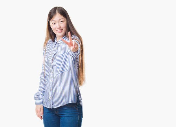Mladá Číňanka izolované pozadí usmívající se dívá do kamery, zachycující prsty tom znamení vítězství. Číslo dvě. - Fotografie, Obrázek