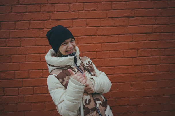 menina adulta de pé em roupas de rua no fundo da parede de tijolo vermelho com espaço de cópia. Mulher em um fundo de parede de tijolo
. - Foto, Imagem