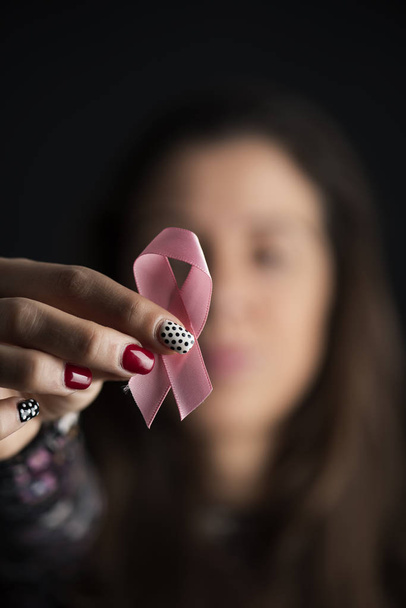 Close-up van een jonge Kaukasische vrouw met een roze lint voor haar gezicht, voor de borst kanker bewustzijn - Foto, afbeelding