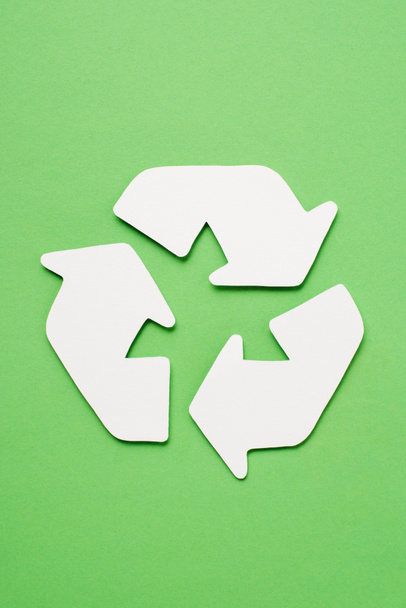 Top view of white trash recycle sign with arrows on green background - Photo, Image