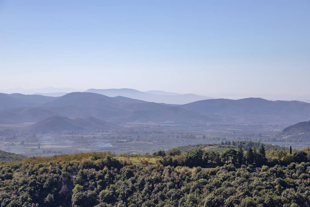 grüne Hügel mit herbstlichem Wald vor der Kulisse von Bergen und blauem Himmel. Griechenland - Foto, Bild