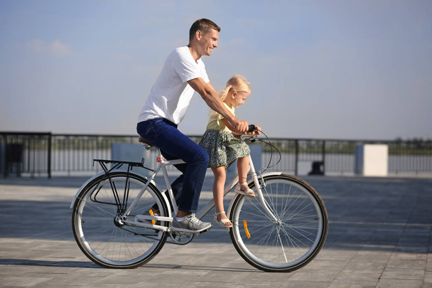 Πατέρας και κόρη ιππασία ποδήλατο σε εξωτερικούς χώρους στην ηλιόλουστη μέρα - Φωτογραφία, εικόνα