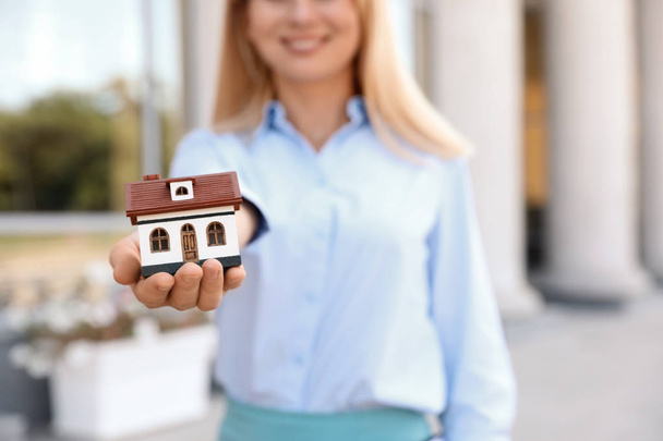 Immobilienmaklerin mit Hausmodell im Freien - Foto, Bild