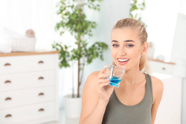 Woman rinsing mouth with mouthwash in bathroom. Teeth care - Photo, image