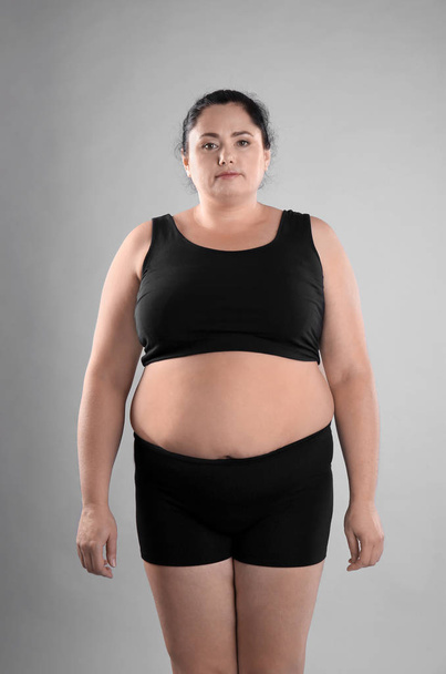 Fat woman on grey background. Weight loss - Фото, изображение