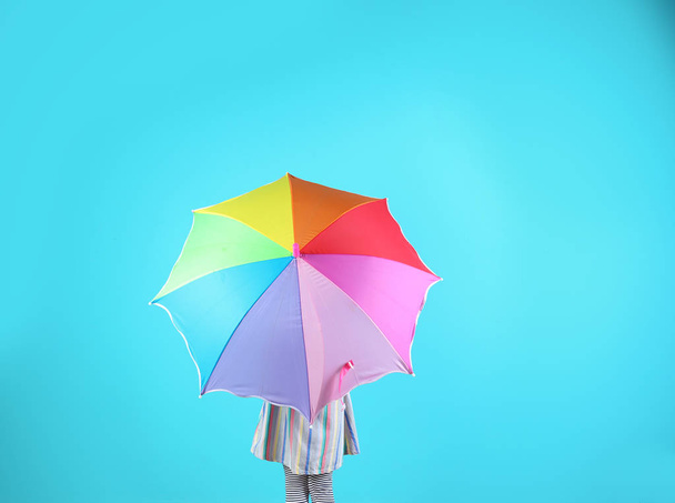 Little girl with rainbow umbrella on color background - Foto, Imagen