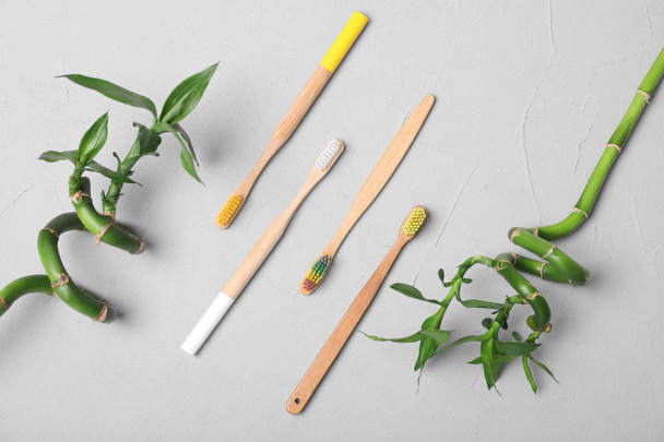 Flat lay composition with bamboo toothbrushes on grey background - Фото, изображение