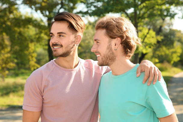 Портрет счастливой гей-пары, улыбающейся в парке
 - Фото, изображение