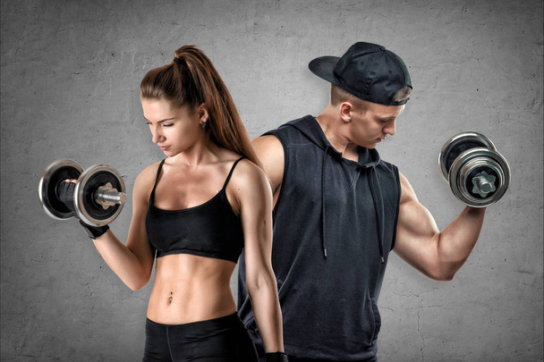 A young muscular woman and a fit man stand on a concrete background. - Photo, Image