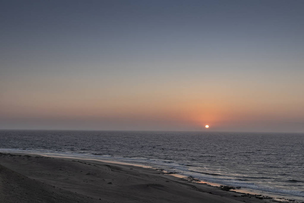 Beautiful sunset on the wild Namibe beach with canyons and desert. - Photo, Image