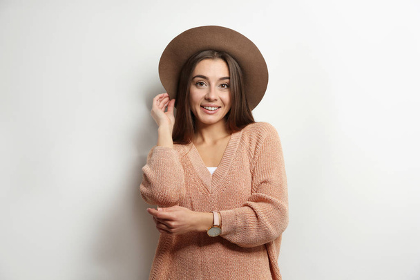 Beautiful young woman in warm sweater with hat on white background - 写真・画像