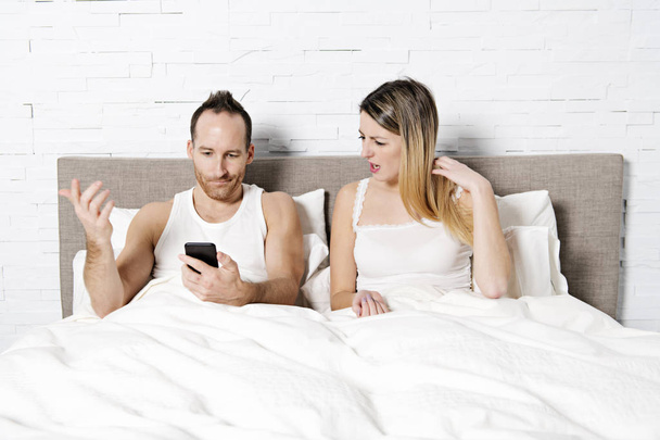 couple using their mobile phone in bed - Zdjęcie, obraz