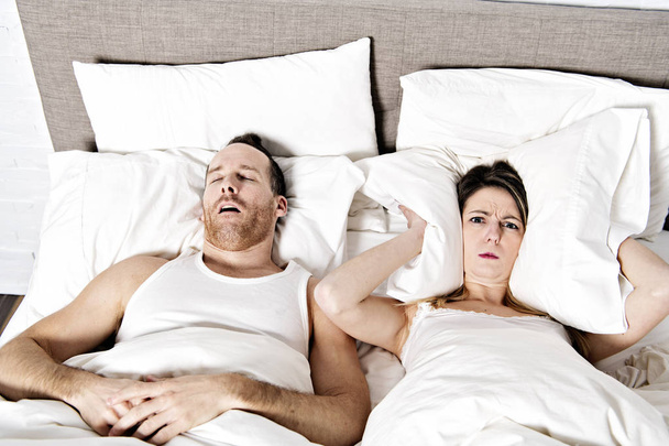 woman blocking ears while man snoring on bed - Photo, Image