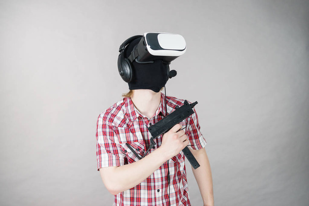 Man gry wideo gra noszenie wirtualnej rzeczywistości urządzenia gospodarstwa pistolet. Sprzęt do grania dla graczy koncepcja. - Zdjęcie, obraz