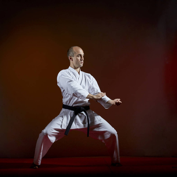 Дорослий спортсмен у карате виконує формальні вправи з карате на темному тлі
 - Фото, зображення